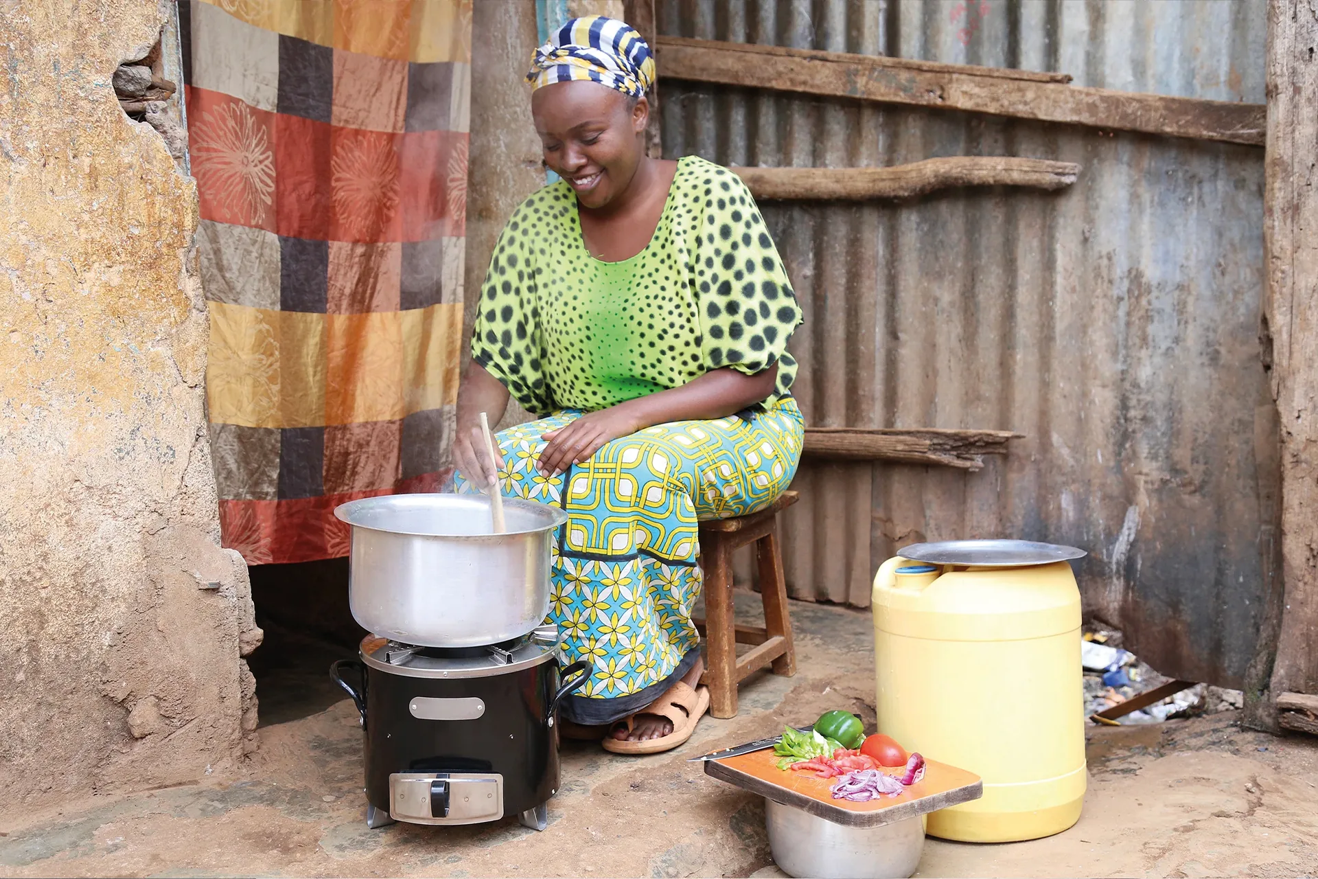 A woman cooks over an open wood fire in a dark, smoke-filled kitchen.