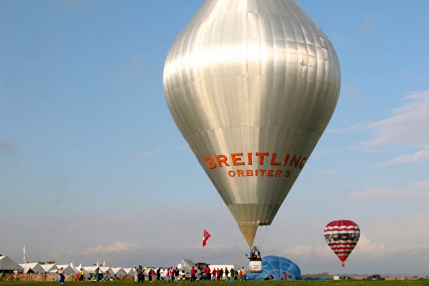 The Breitling Orbiter 3 balloon being prepared for launch, surrounded by crowds and tents.