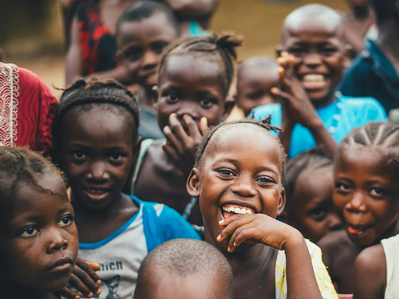A group of smiling children look toward the camera.